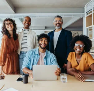 Grupo de personas diversas en oficina sonriendo al estar en una sala de reuniones