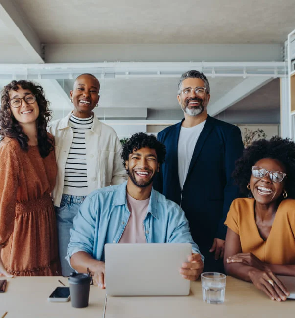 Grupo de personas diversas en oficina sonriendo al estar en una sala de reuniones