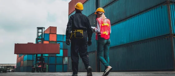 Dos trabajadores caminando en terminal de contenedores portando equipo de seguridad