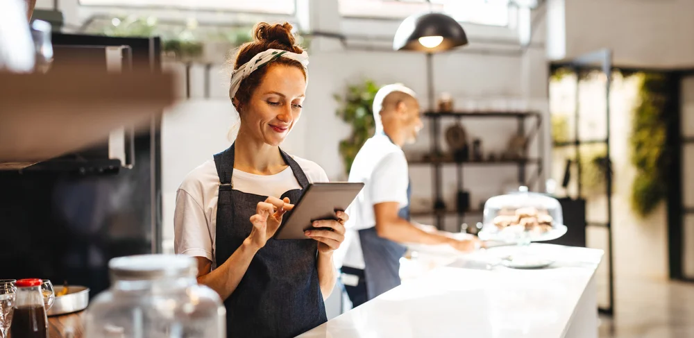 Mujer cajera en cafetería utilizando tablet