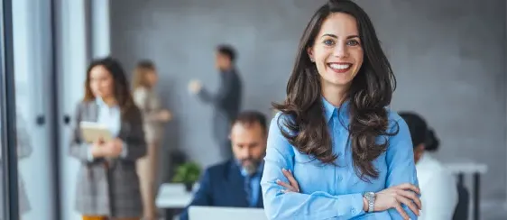 Mujer ejecutiva sonriendo con pose segura delante de más personal ejecutivo desenfocado