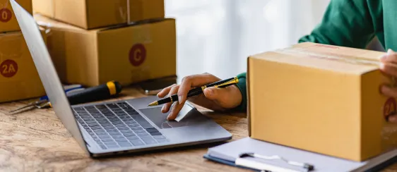 imagen de una persona trabajando con una computadora entre cajas de carton