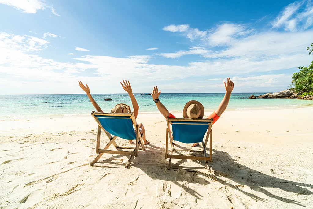 Dos personas sentadas en la playa sobre una silla